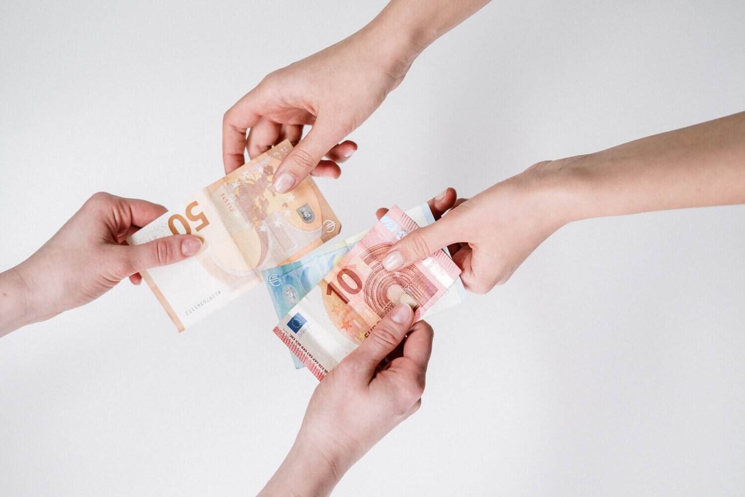 Hands exchanging euro banknotes against a plain background.