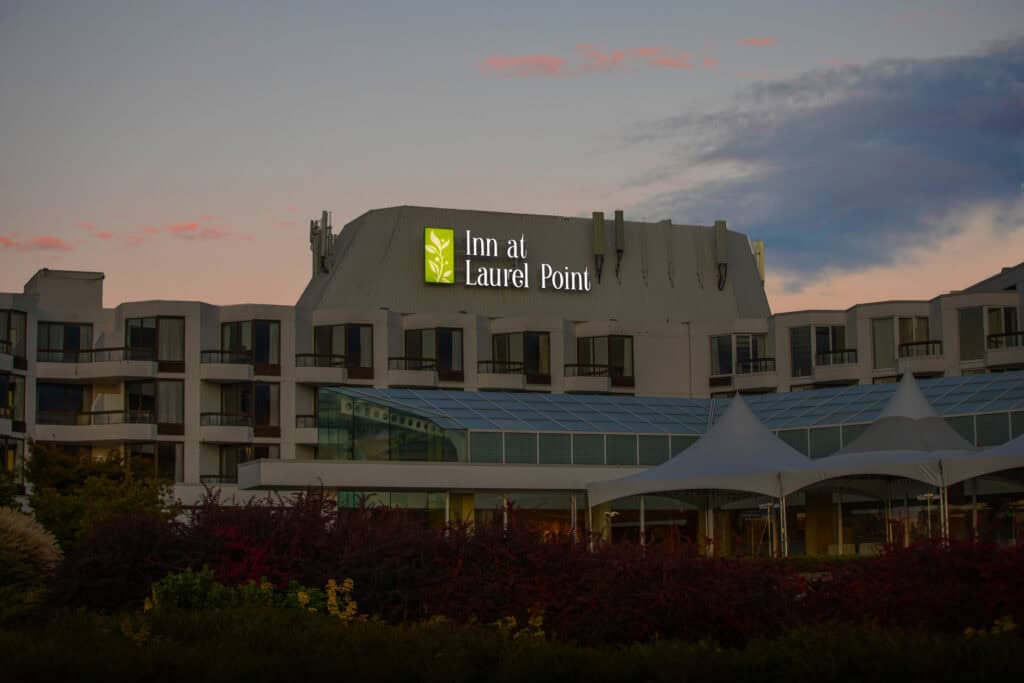 Exterior view of the Inn at Laurel Point with illuminated sign at dusk.