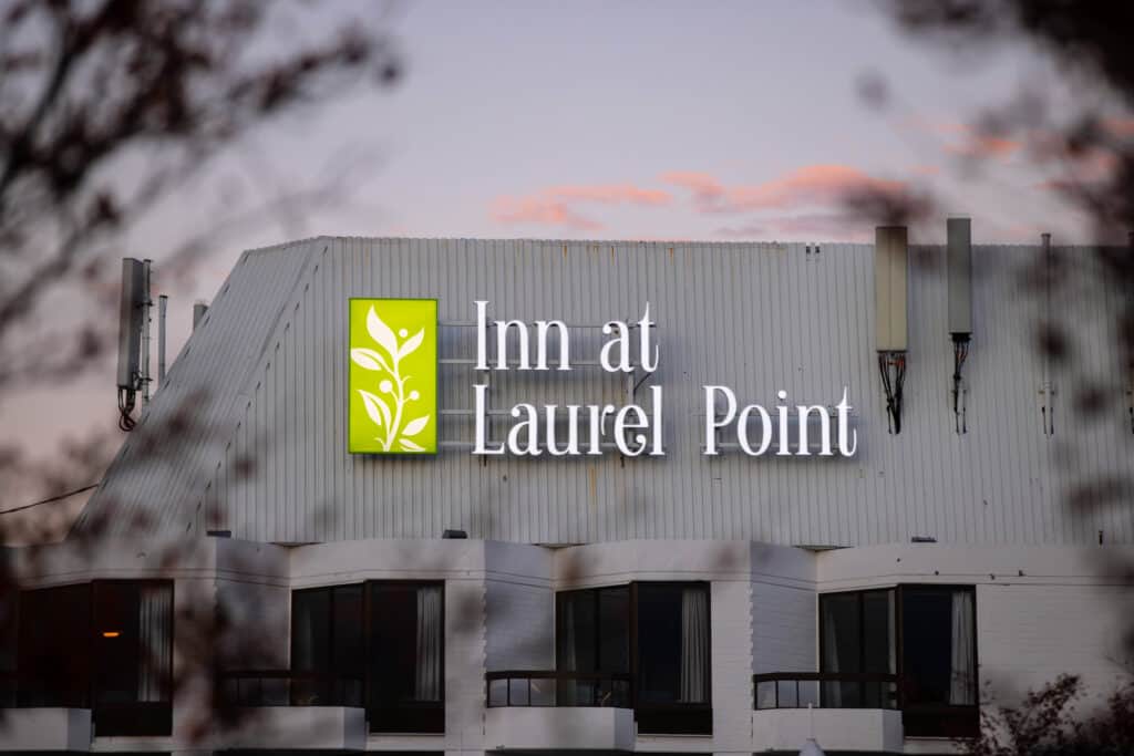 Sign for Inn at Laurel Point with green logo and white text.