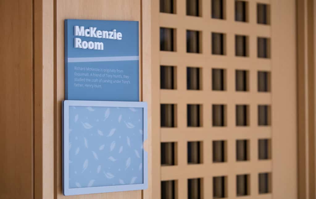Blue McKenzie Room sign with informational plaque in a modern interior setting.