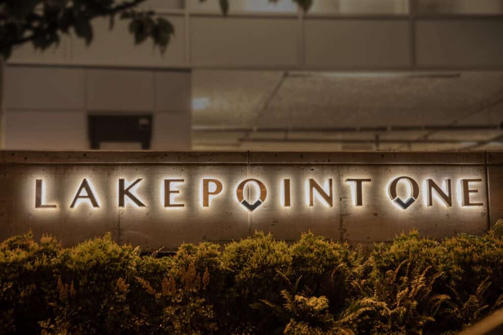Modern illuminated Lakepoint One sign on a brick wall at night.