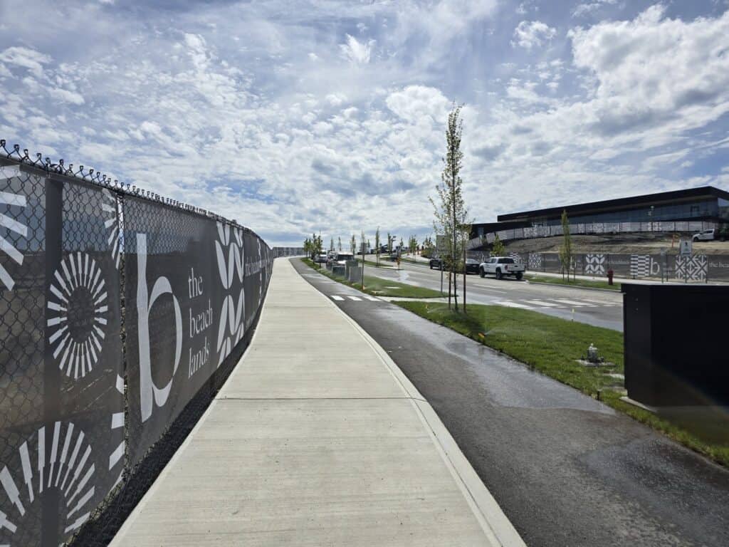 Outdoor sidewalk with decorative metal fence and modern commercial buildings in the background.