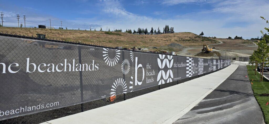 Signage featuring "The Beachlands" branding along a fence.