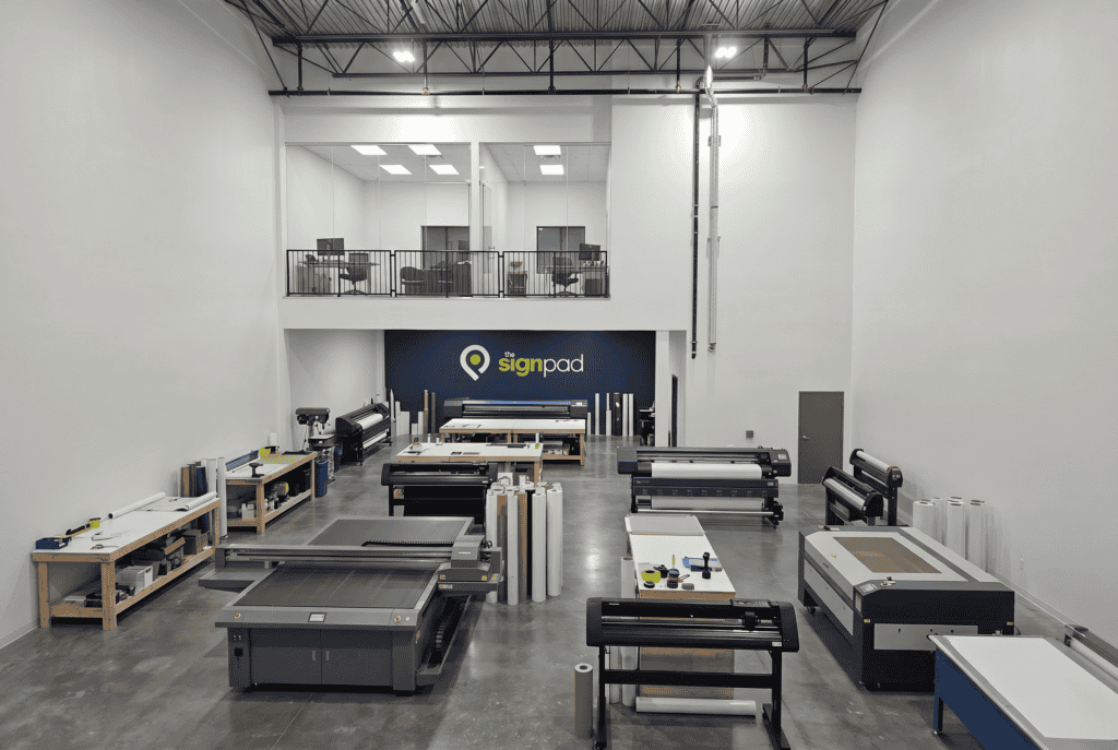 High-tech sign making equipment in a spacious workshop for custom signs and vehicle wraps.