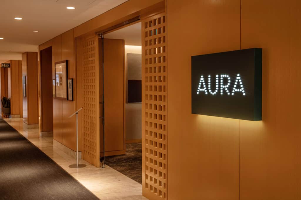 Modern office lobby with illuminated "AURA" sign on wall.