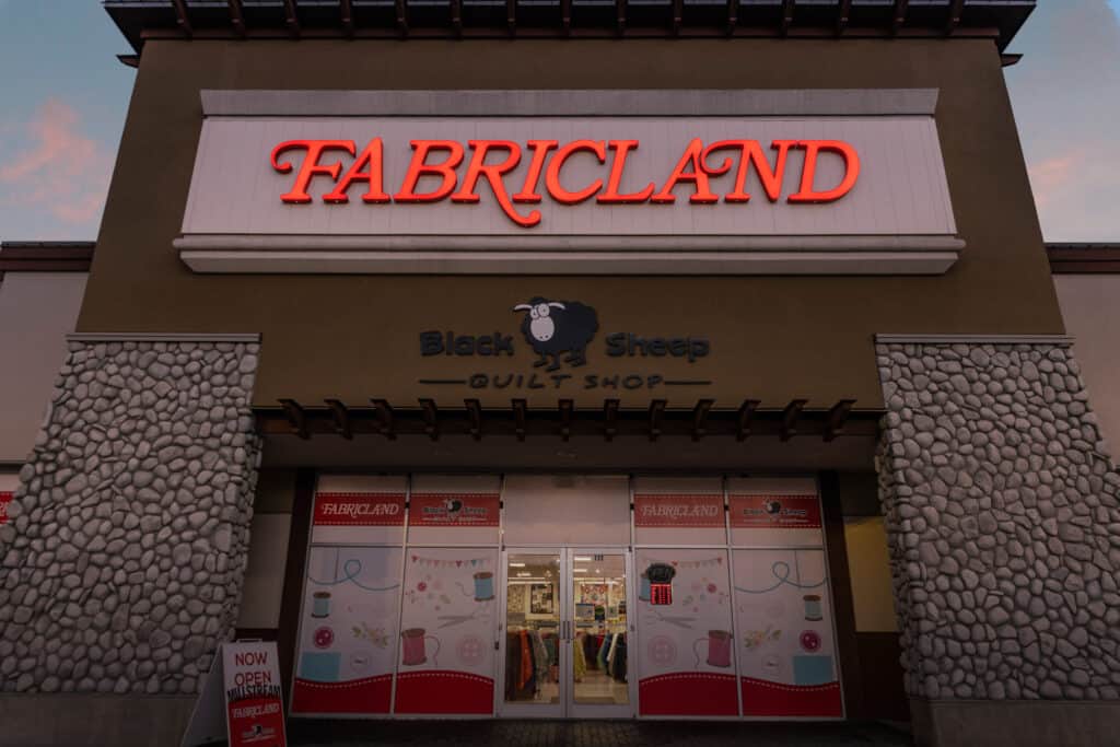 Fabricland sign illuminated at storefront.