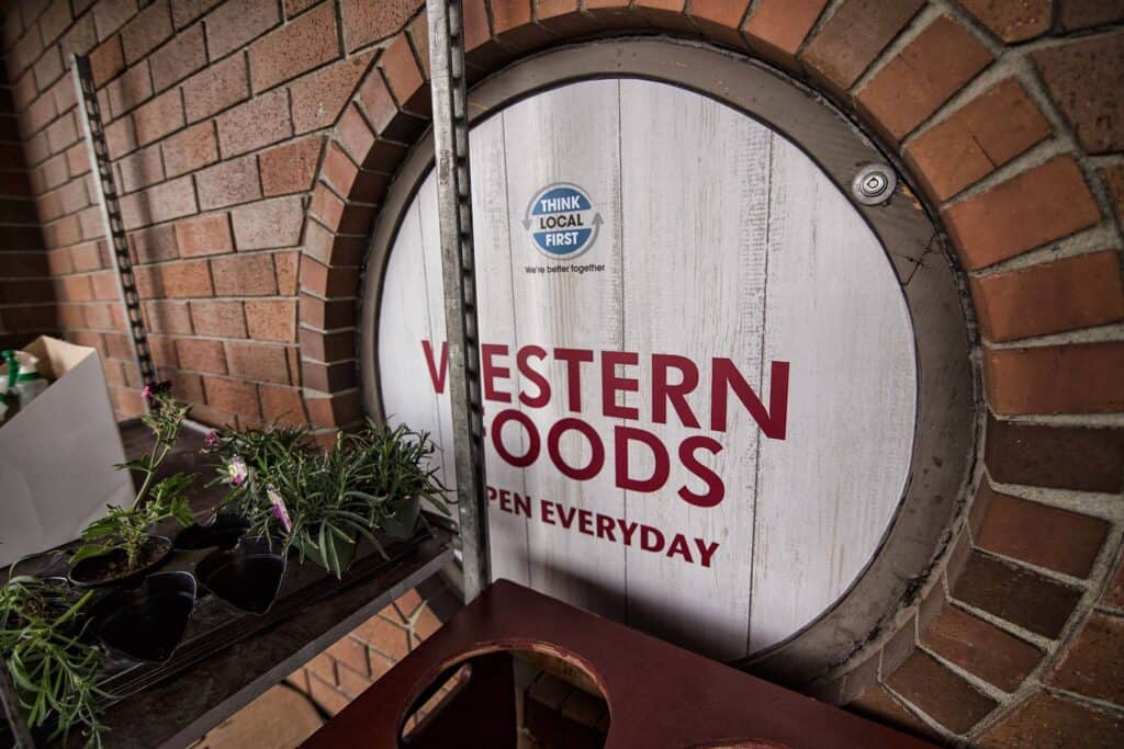 Circular Western Foods sign on brick wall, open every day.