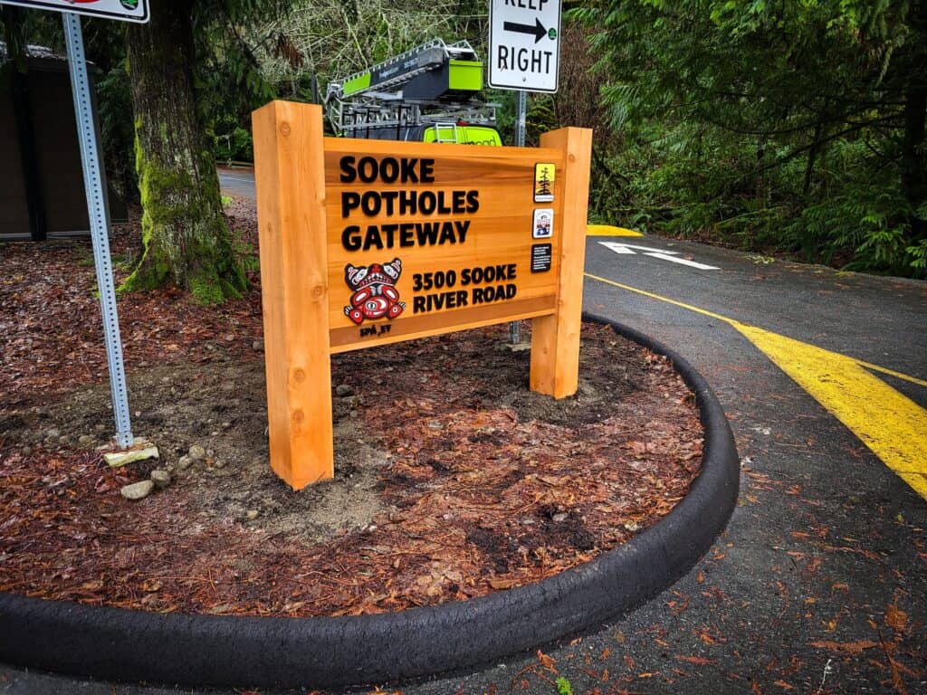 Sooke Potholes Gateway sign on a wooded roadside in Victoria, BC.