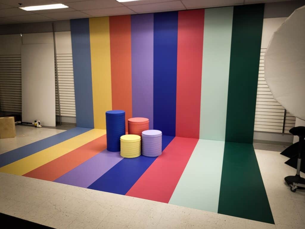 Vibrant striped background with stacked cylindrical props for creative photo shoots.