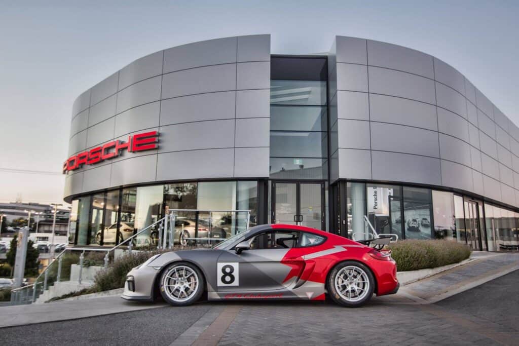 Modern Porsche dealership with a sleek sports car parked outside.