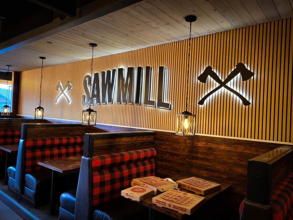 Sawmill restaurant sign with crossed axes on wooden wall.