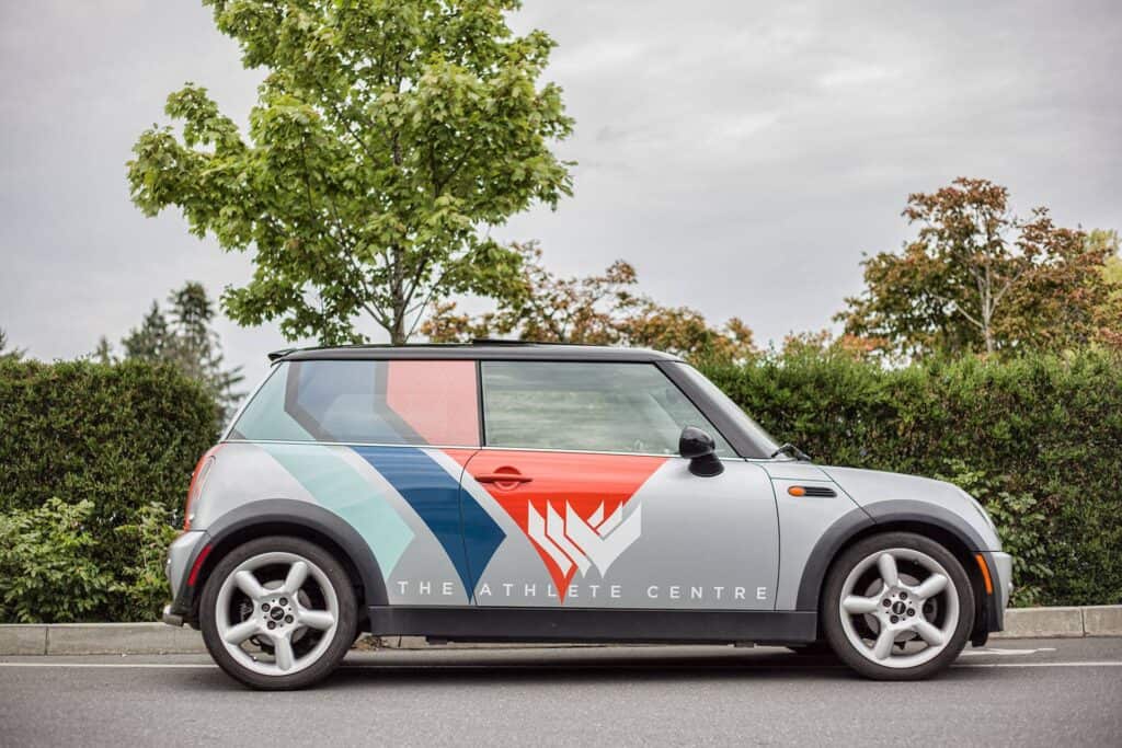 Custom vehicle wrap featuring The Athlete Centre logo on a compact car in Victoria.