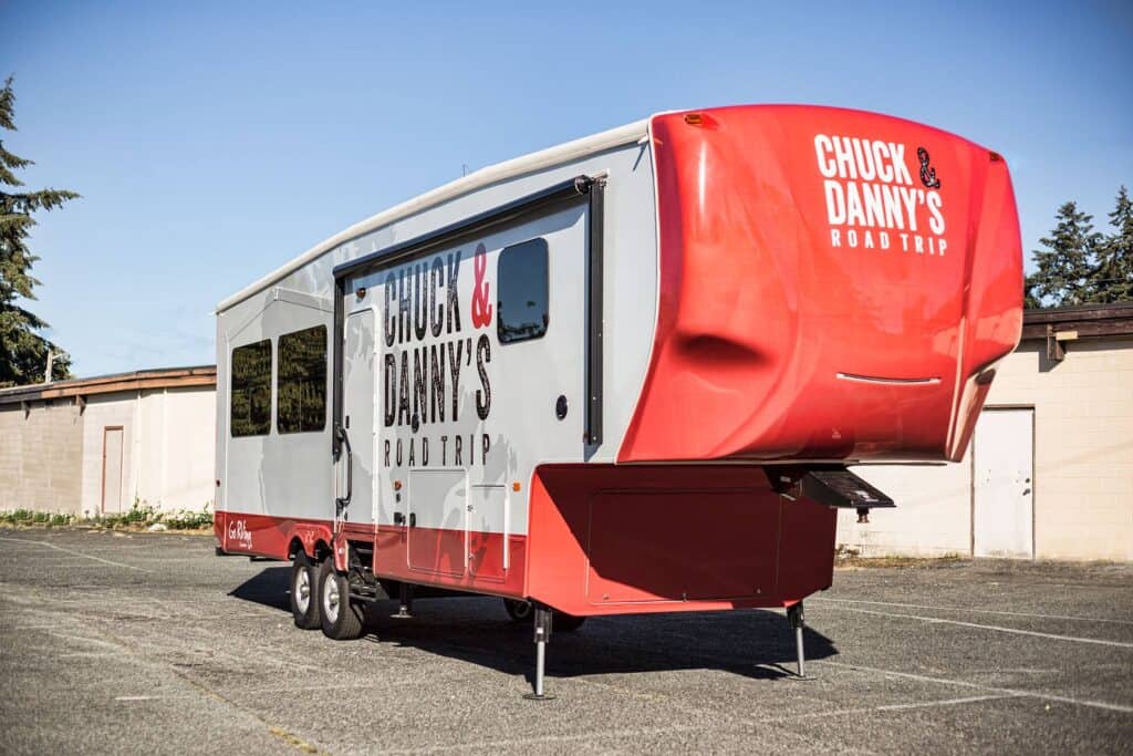 Vehicle wrap featuring "Chuck & Danny's Road Trip" branding and vibrant red and white design.