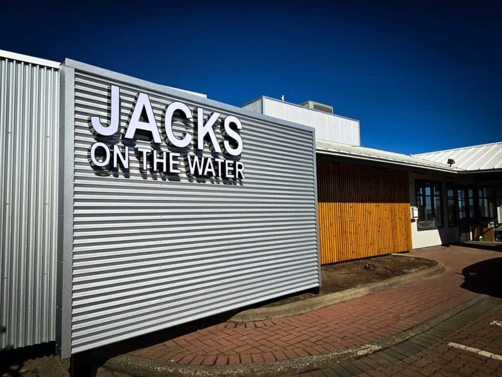 Signage for Jacks on the Water restaurant in Victoria, featuring bold lettering on a modern metal fa.
