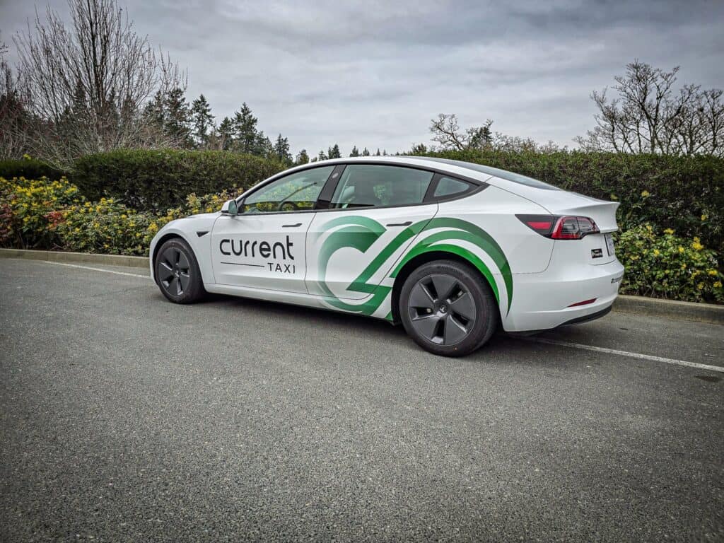 Electric taxi with custom green and white branding for Current Taxi.