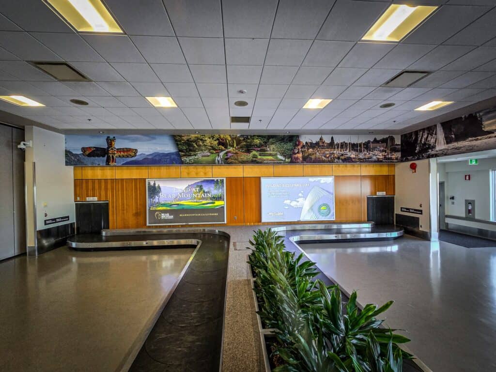 Modern airport signage display with digital screens and scenic backdrop.