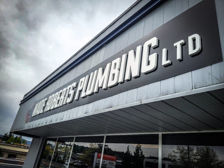 Exterior view of a custom business sign reading "LITTLE ROBERTS PLUMBING LTD" on a commercial buildi.