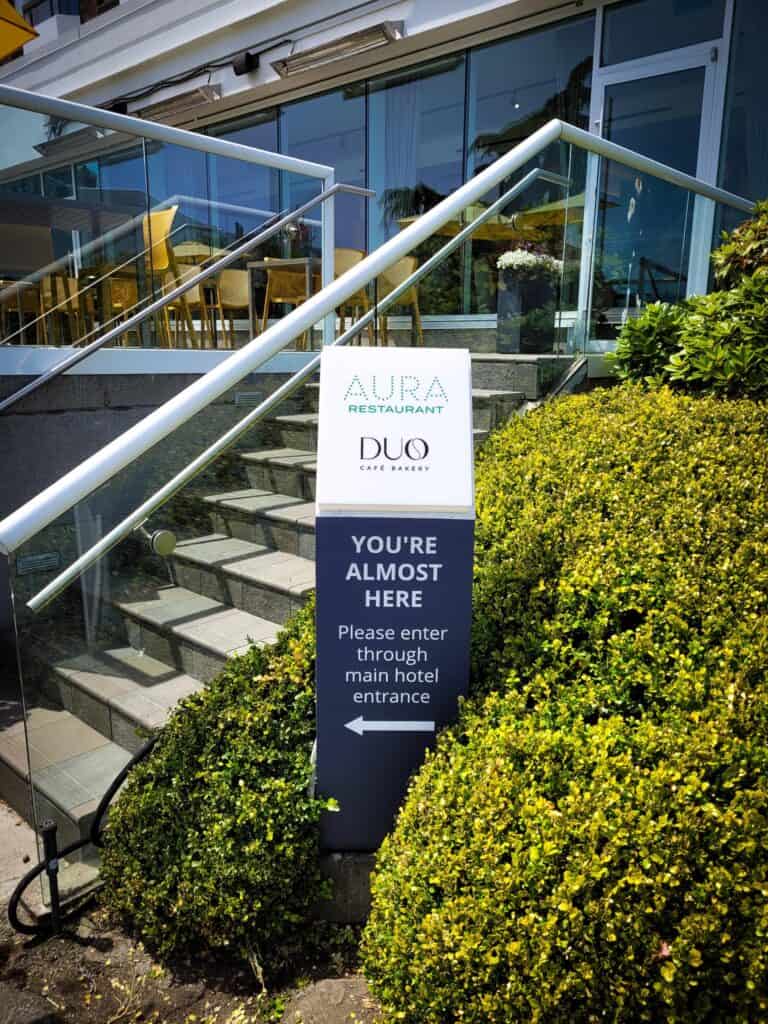 Signage for Aura Restaurant and Duo Cafe Victoria with directional information.