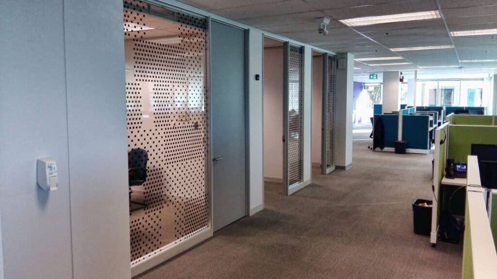 Office workspace with glass partitions and ergonomic furniture.