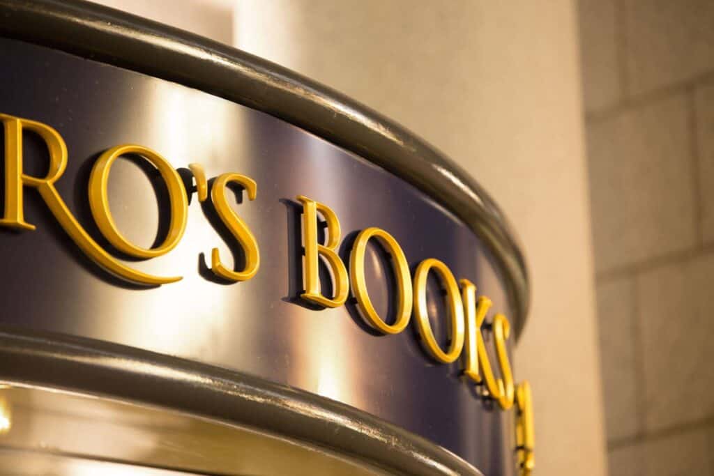Signage display with "RO'S BOOKS" in gold letters on a metallic background.