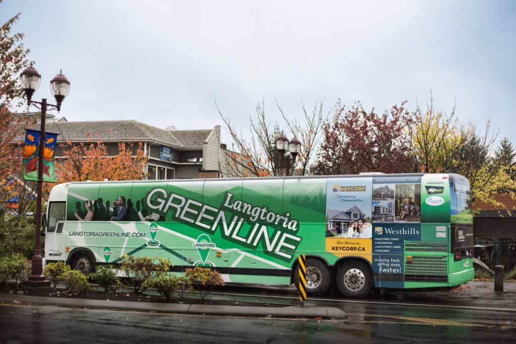 Greenline bus with advertising in Victoria on a rainy day.