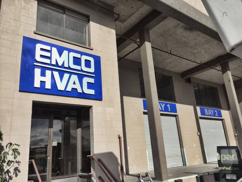 Modern blue and white EMCO HVAC sign on building exterior.