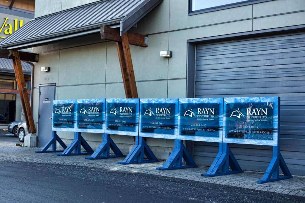 Row of blue A-frame signs advertising Rayn Properties Ltd. outside a commercial building.