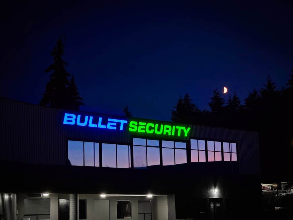 Bullet Security sign illuminated on building facade at night.