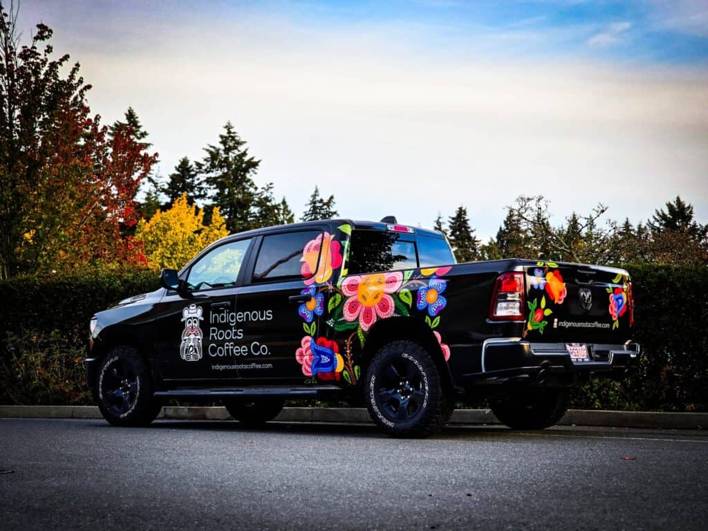 Black pickup truck with vibrant Indigenous-themed wrap for Indigenous Roots Coffee Co.