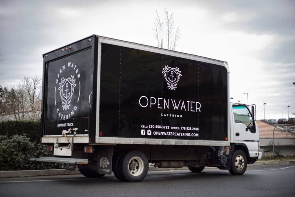 Catering truck with Open Water logo and branding on black vehicle.