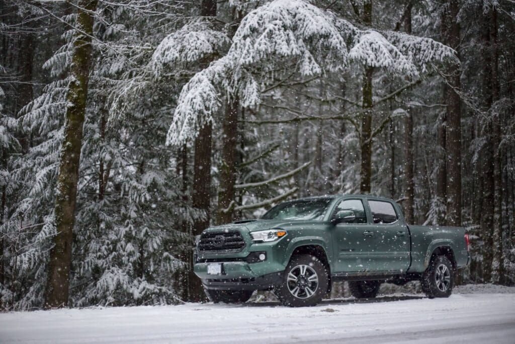 Custom vehicle wrap on a pickup truck in a snowy forest setting.