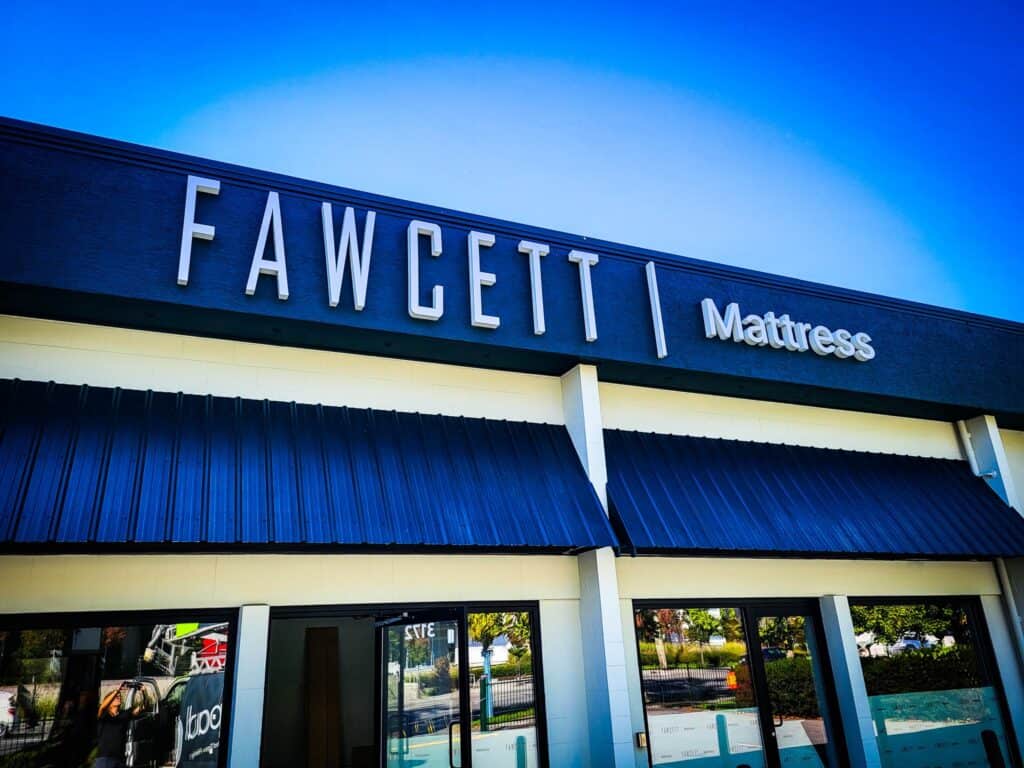 Exterior view of Fawcett Mattress store sign on building facade.