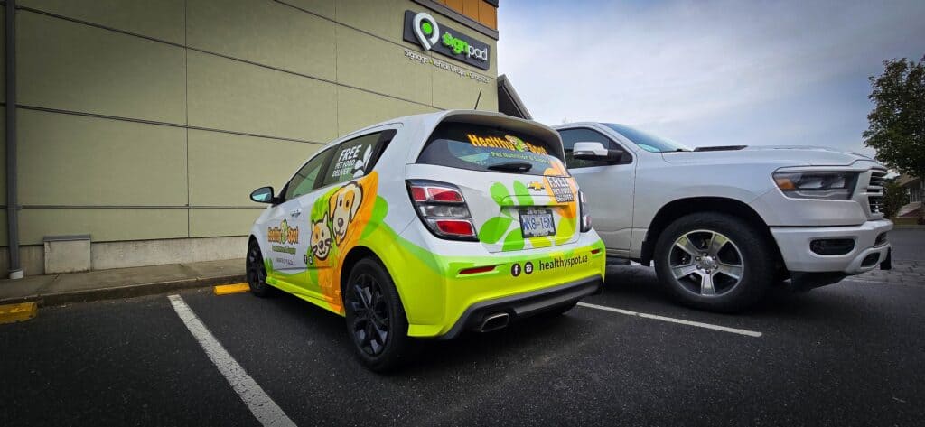 Car with custom signs and vehicle wraps parked outside a building in Victoria.
