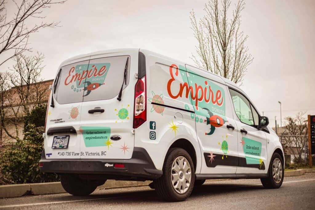 Vehicle wrap with Empire logo and colorful graphics on a white van.