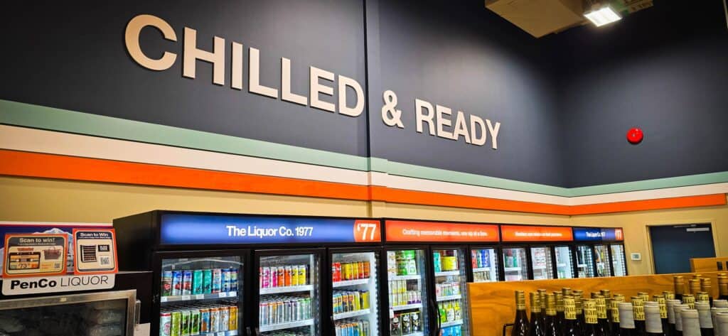 Interior view of a liquor store with custom signs and refrigerated beverage displays.