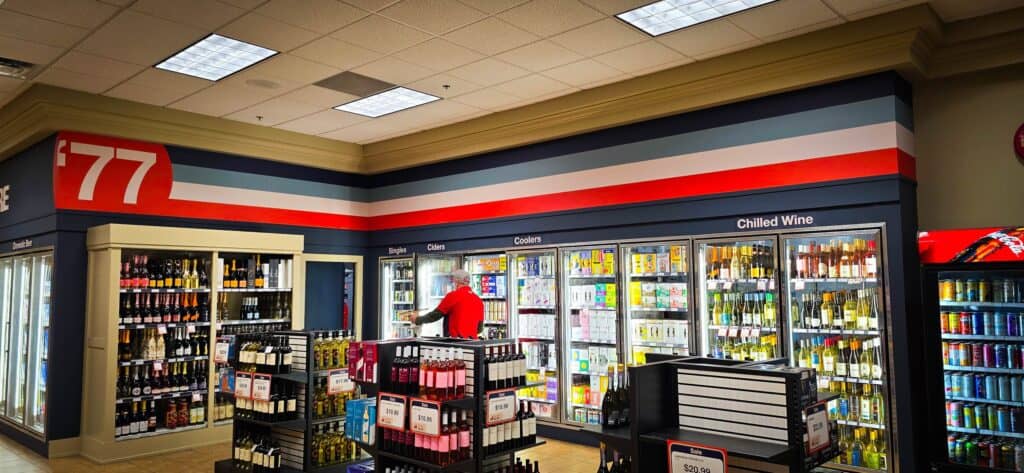 Interior view of a convenience store with custom signs and refrigerated beverage displays.