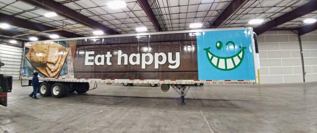 Large vehicle wrap with "Eat happy" message and a smiling face graphic in Victoria.