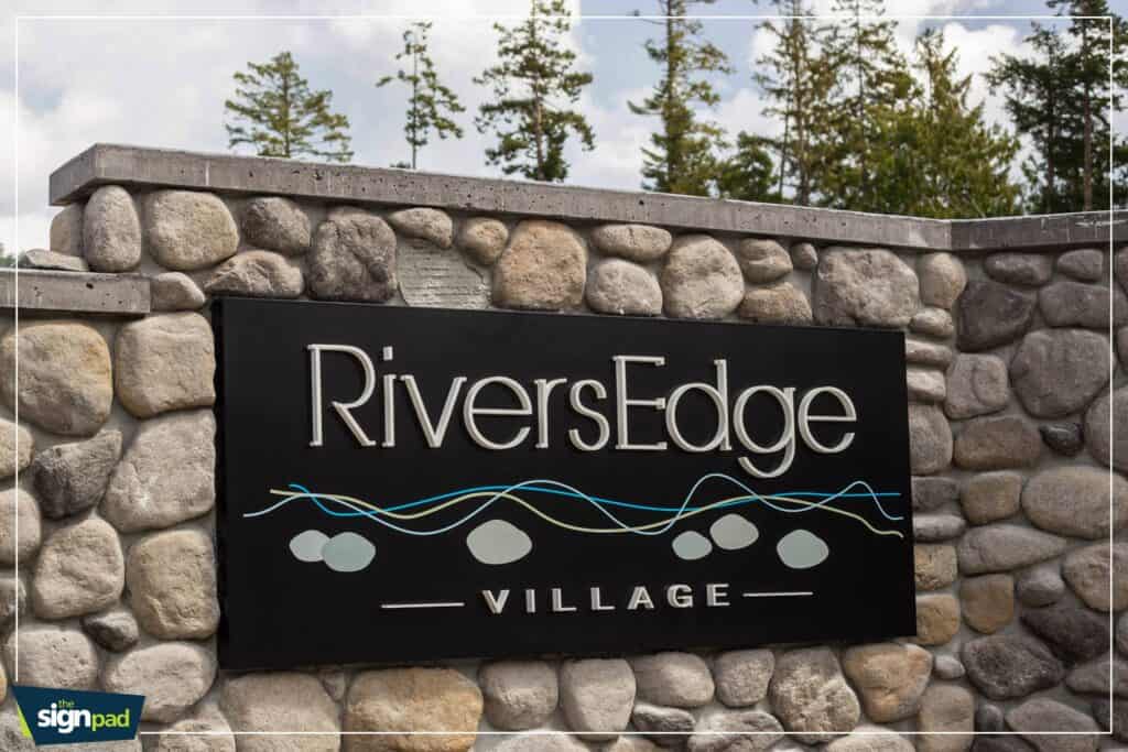 Custom River Village sign on stone wall in Victoria.