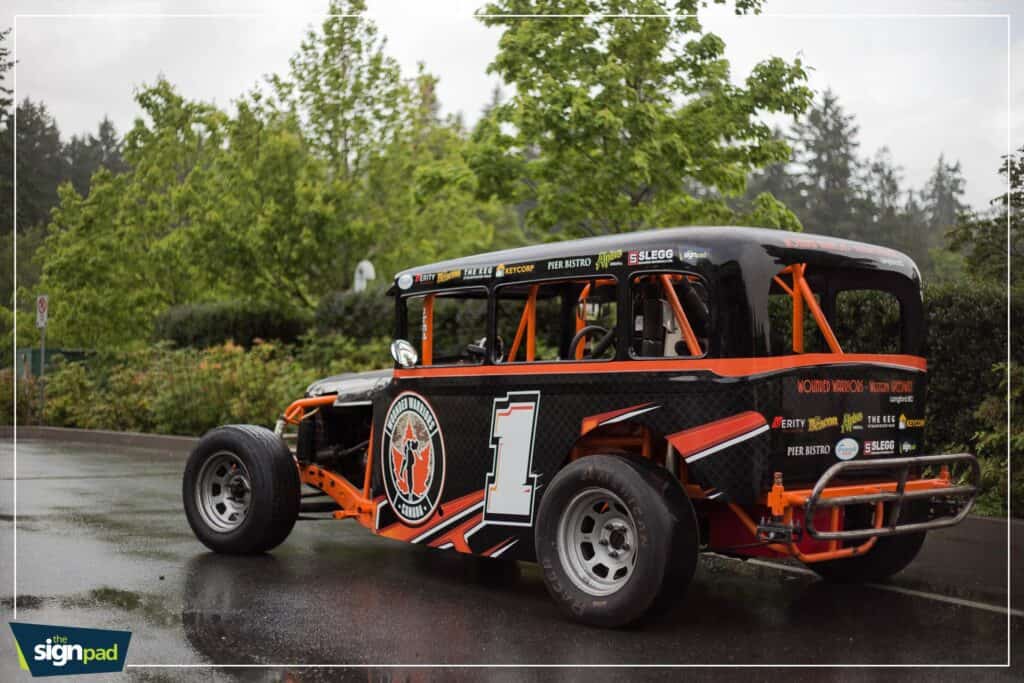 Custom race car with vibrant orange and black vehicle wrap design.