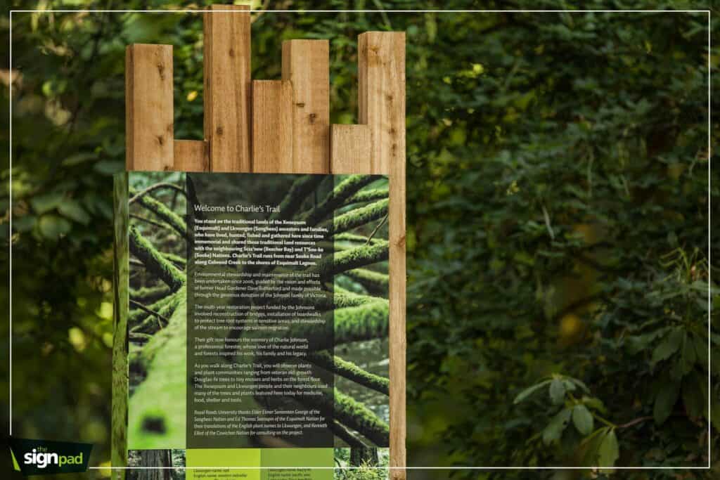 Welcome sign for Charlie’s Trail in Victoria, featuring a wooden frame and detailed informational pa.