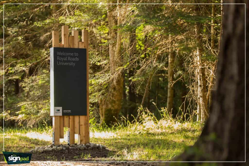 Welcome sign for Royal Roads University in a wooded area.