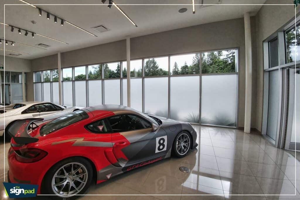 Custom car wrap on a sleek sports car inside showroom.