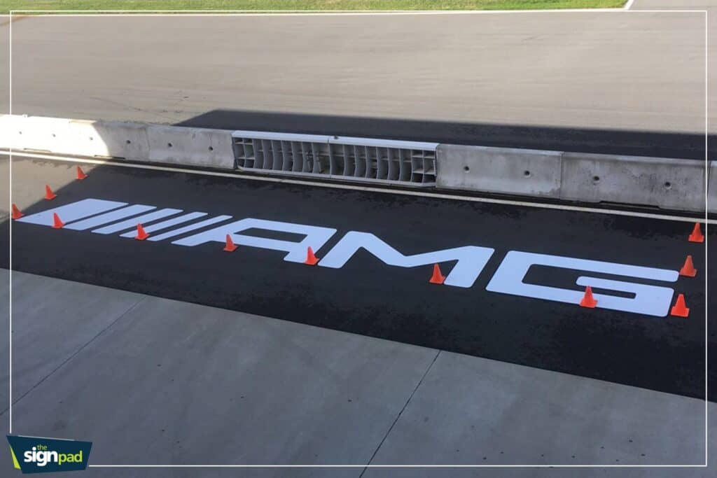 Sign pad with "AMG" logo painted on the road surface.