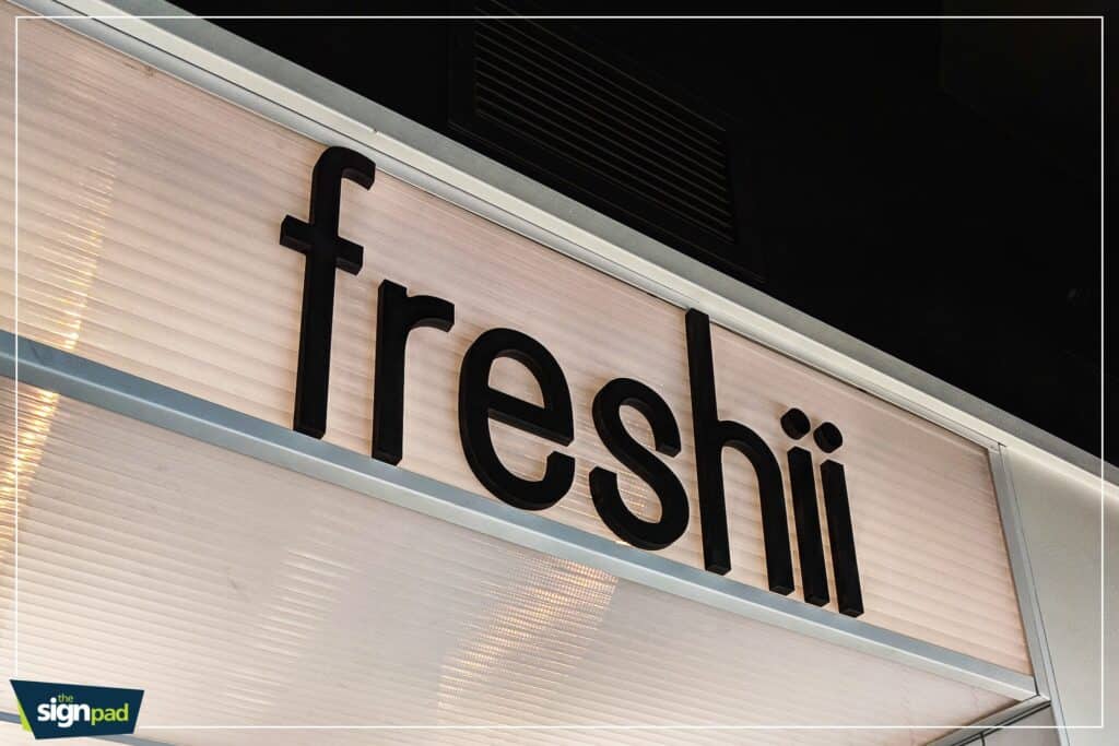 Custom Freshii restaurant sign with bold black lettering on a light background.