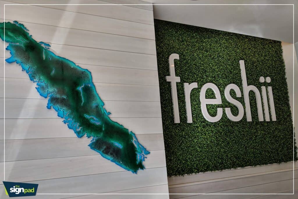 Custom sign with "freshii" logo on a green wall background.
