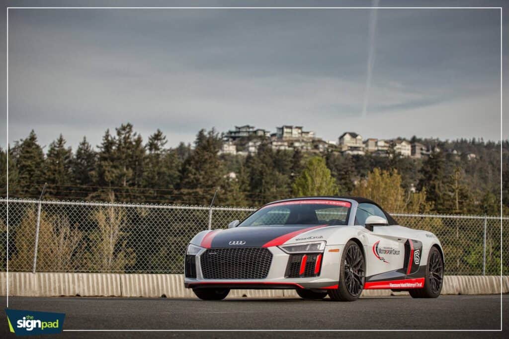 Modern Audi sports car parked on a racetrack with scenic background.