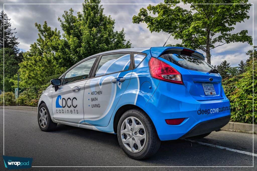 Blue car with custom signage for Deep Cove Cabinets, kitchen, bath, and living room renovations.