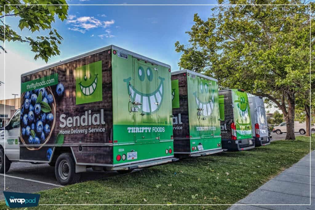 Fleet of Sendial food delivery trucks with cheerful green smiley logo parked outdoors.