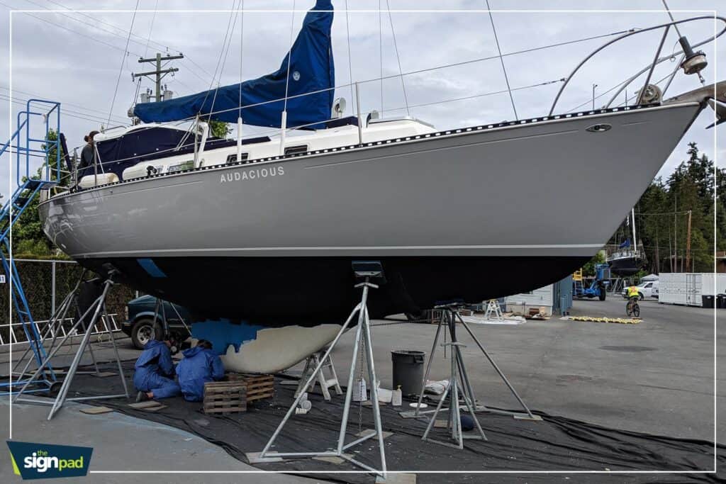 Boat with a blue sail cover on a boat lift in a boatyard.
