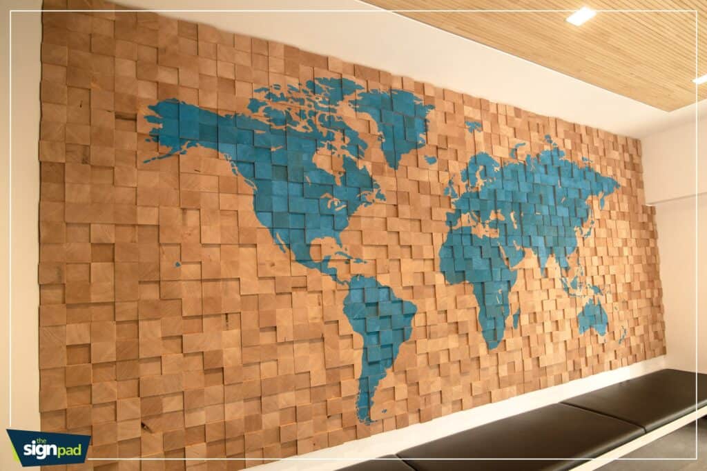 Decorative world map wall art with blue continents on wooden blocks in interior space.